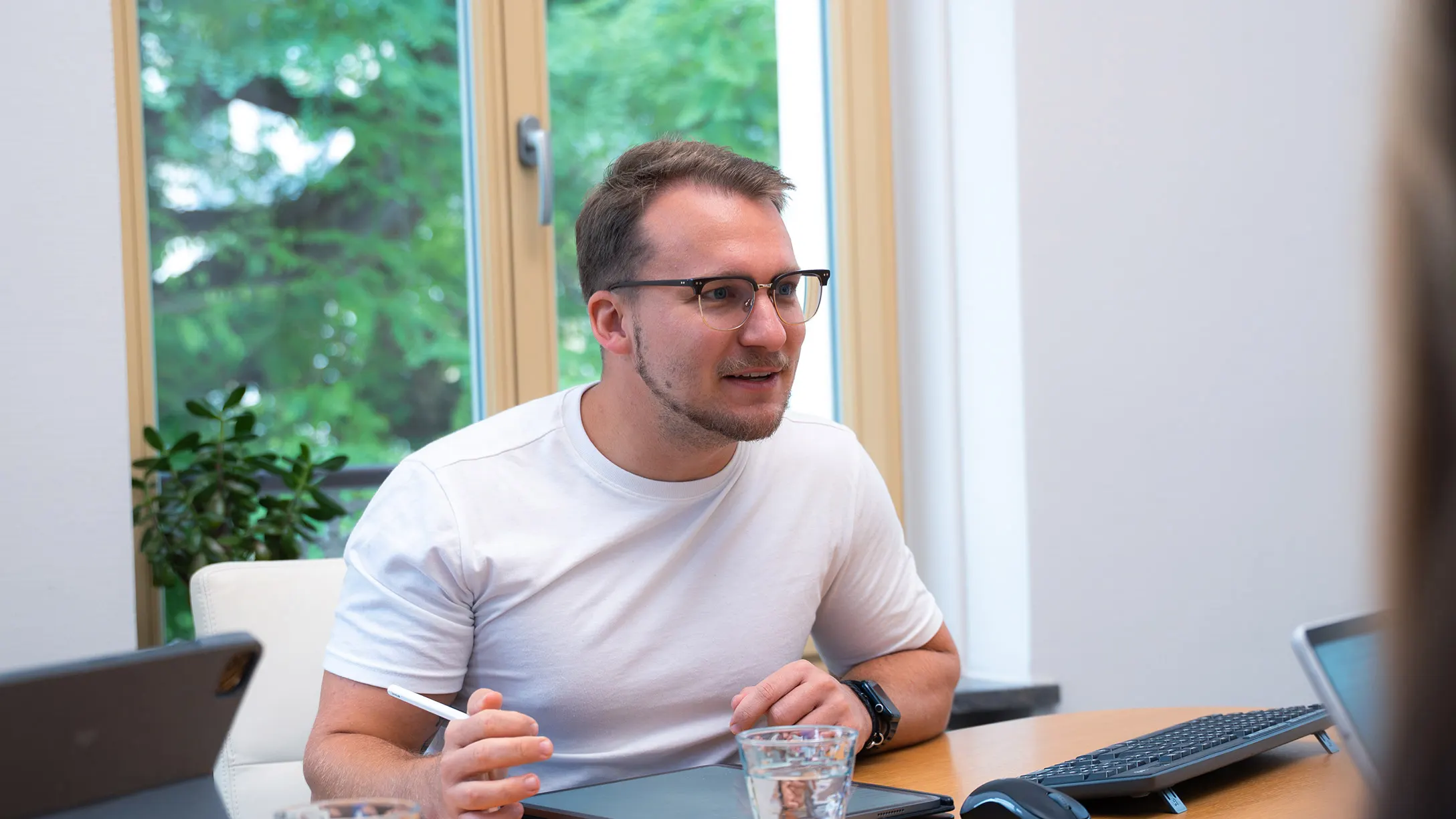 Kollege arbeitet konzentriert an seinem Schreibtisch am Fenster